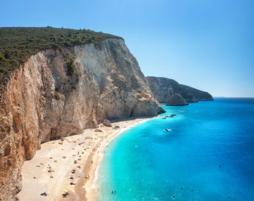 Aerial View Of Blue Sea, Rock, Sandy Beach At Sunny Day In Summer